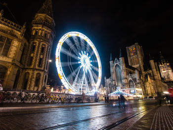 Illuminated ferris wheel in city at night