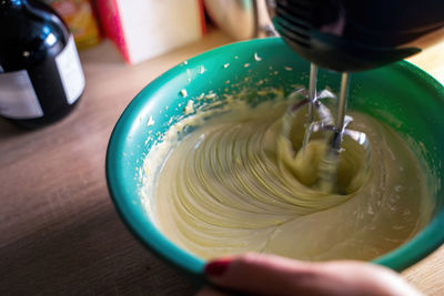 Cooking sweet sponge cake at home - view of a machine whipping liquid cream mascarpone with sugar