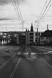 Railroad tracks by city with church against sky