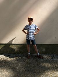 Full length portrait of boy standing against built structure