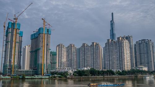 Panoramic view of modern buildings by river against sky
