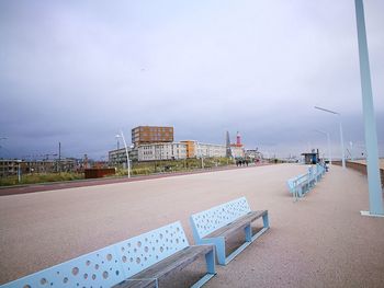 Empty road by buildings against sky