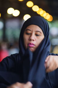 Portrait of indonesian muslim woman wearing black hijab with bokeh.