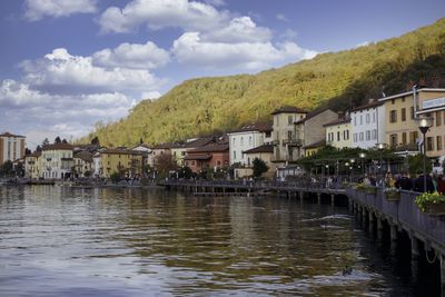 Buildings by river against sky
