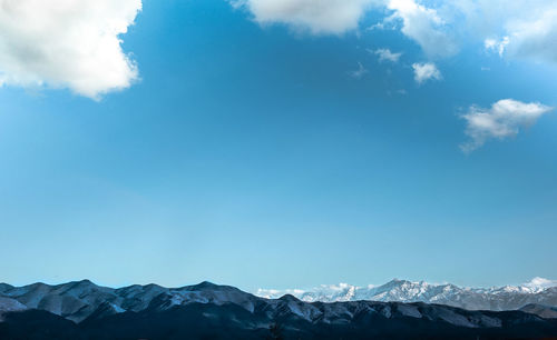 Scenic view of snowcapped mountains against blue sky