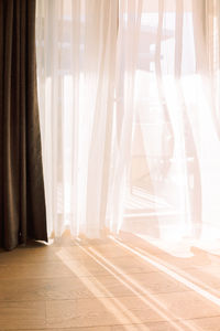 Modern room interior with an open window in minimal style. transparent tulle with morning sun rays 