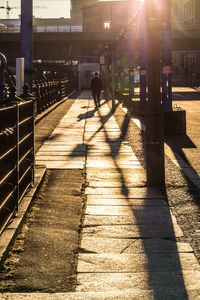Silhouette man walking on sidewalk in city
