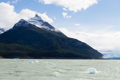 Scenic view of sea and snowcapped mountains against sky