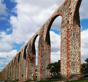 Low angle view of bridge against cloudy sky