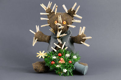 Close-up of teddy bear with clothespins and christmas tree against gray background