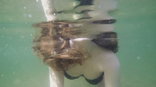 Midsection of woman swimming underwater