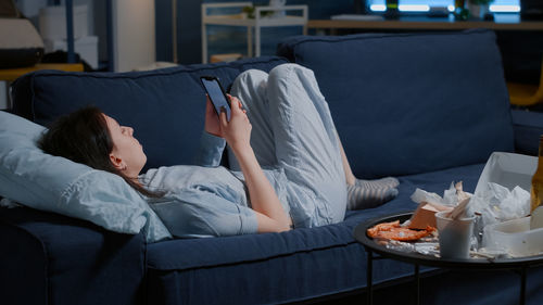 Midsection of woman lying on sofa