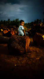 Full length of boy sitting on log