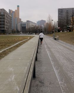 Woman running on footpath against buildings