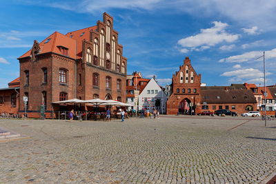 People on street amidst buildings in town against sky