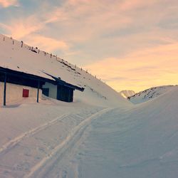 Scenic view of snow covered houses against sky during sunset