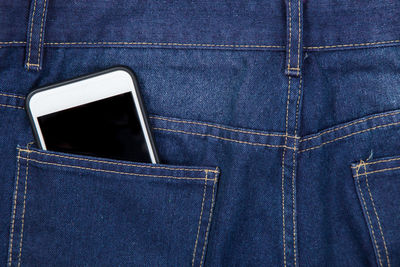 Close-up of mobile phone in blue jeans back pocket