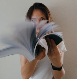 Portrait of young woman holding face against white background