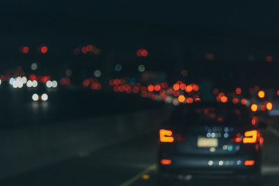 Defocused image of illuminated city against sky at night