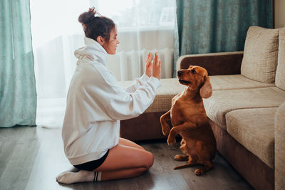 Side view of woman with dog playing at home