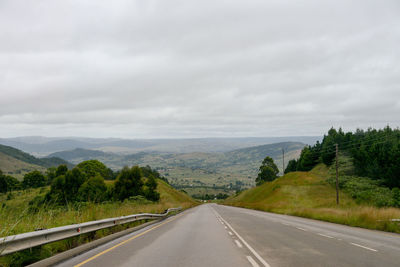 Empty road by mountains against sky