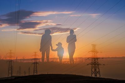 Silhouette people on beach against sky during sunset