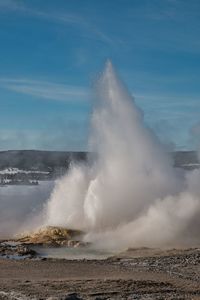 Waves splashing on shore against sky