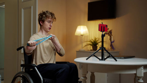 Young man exercising while vlogging at home