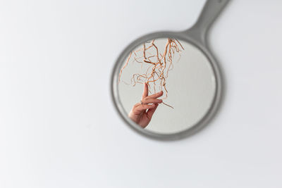 Cropped hand of woman reflecting in hand mirror