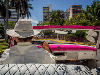 Rear view of man driving car on sunny day