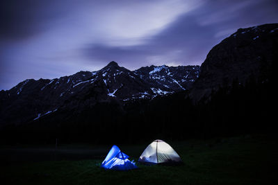 Tent in mountains against sky at night