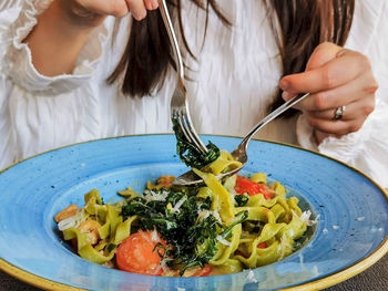 Close-up shot of woman eating pasta in italian restaurant.