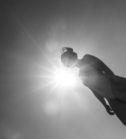 Low angle view of sunlight streaming through hand against sky