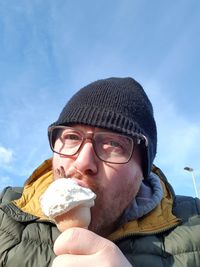 Portrait of mid adult man eating ice cream against blue sky