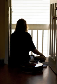 Rear view of woman sitting by table at home