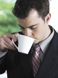 Close-up of businessman drinking coffee while sitting in office