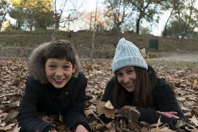 Portrait of mother and son lying down on ground during autumn