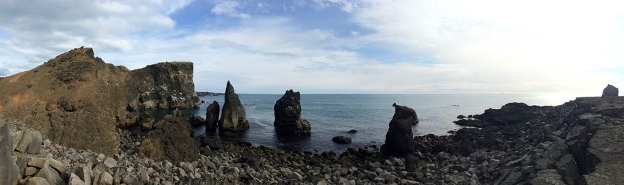 Panoramic view of cliff by sea against sky