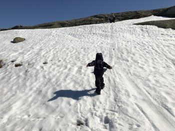 Full length of person walking up a snowcapped mountain