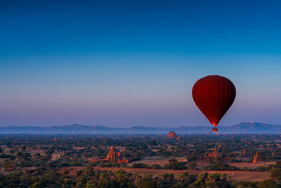 Hot air balloon flying over landscape against blue sky