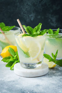 Two glass with lemonade or mojito cocktail with lemon and mint, cold refreshing drink.