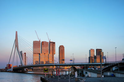 Bridge over river in city against clear blue sky