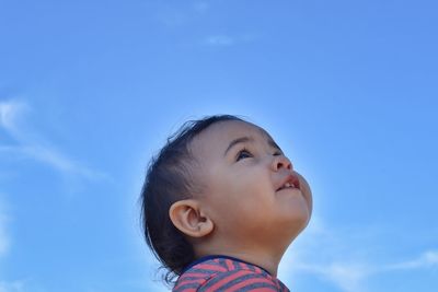 Portrait of cute girl looking away against blue sky