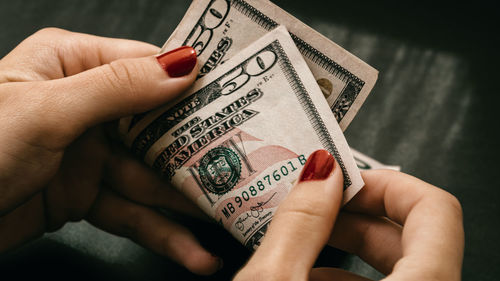 Cropped hand of person holding paper currency against black background