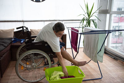 A disabled person on a wheelchair washes laundry