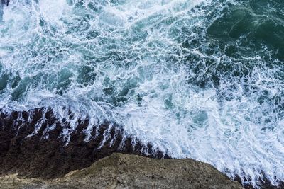 High angle view of waves splashing on rocks