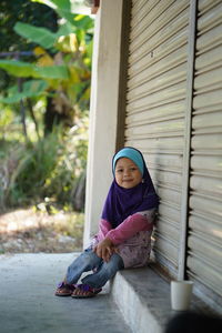 Portrait of girl sitting by closed shutters