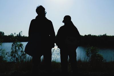 Silhouette man standing by lake against sky