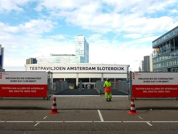 Road sign on street in city against sky