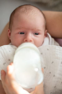 A woman feeds a newborn with modified milk from a bottle. newborn feeding concept.